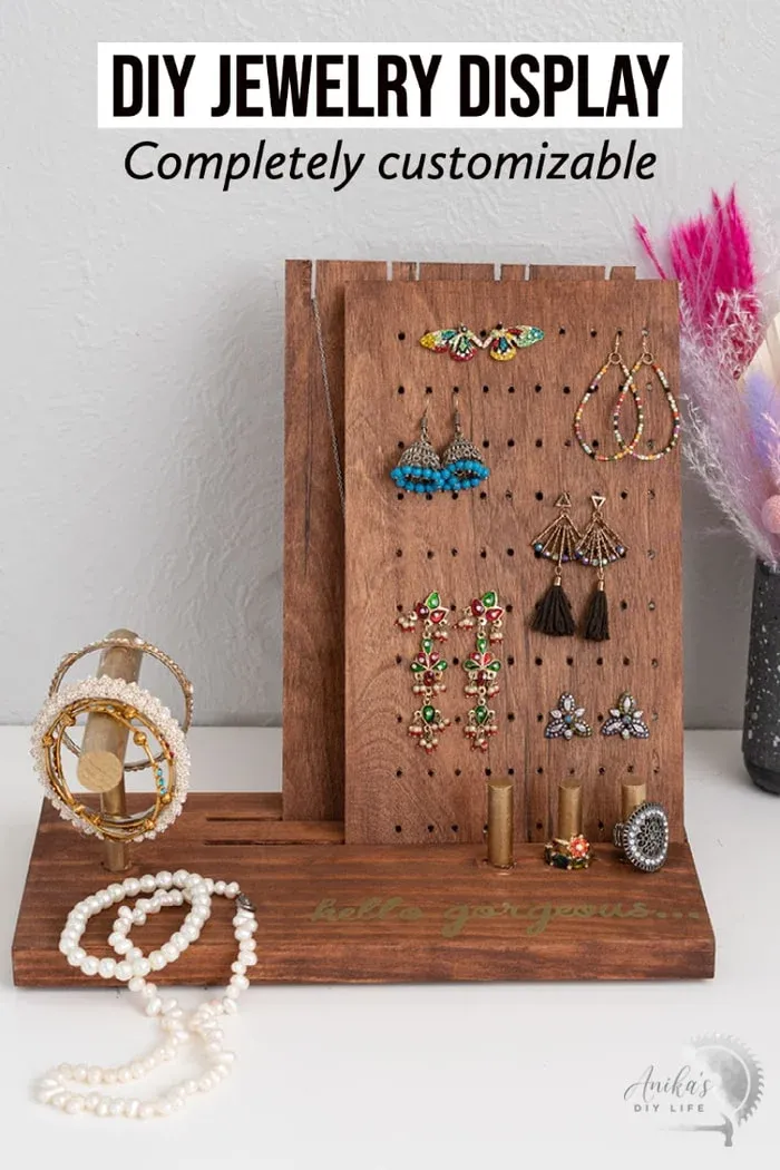 A custom wooden jewelry display base stained in dark walnut, featuring angled grooves for display cards and wooden dowels for holding rings and bracelets.