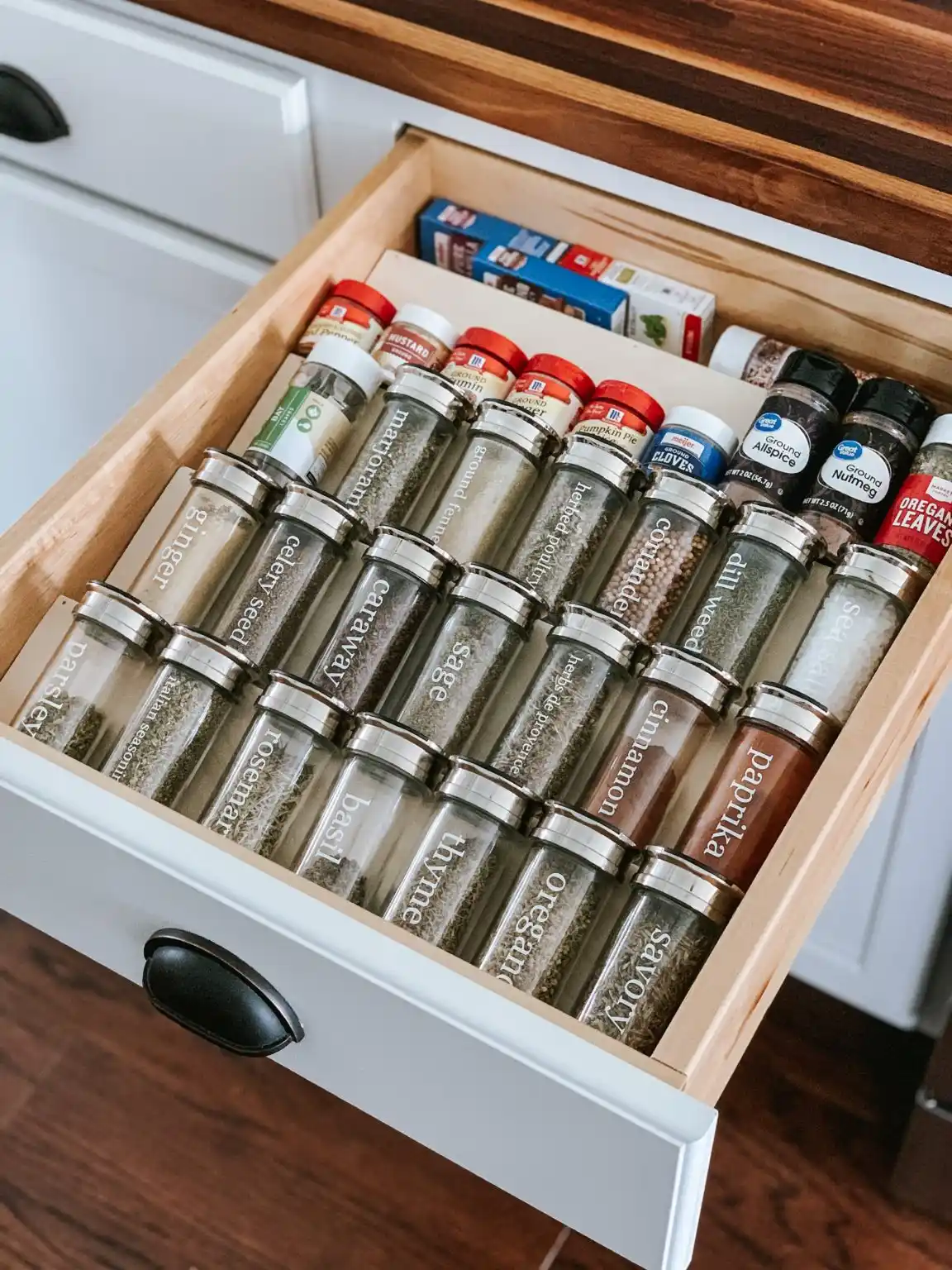 An open kitchen drawer showing a beautifully organized wooden tiered spice rack, making for a highly functional and a perfect project to sell.