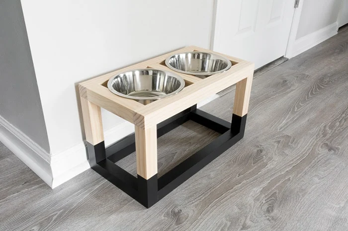 A modern, handmade wooden raised dog bowl stand in a bright kitchen, serving as a highly profitable wood project to sell to pet owners.