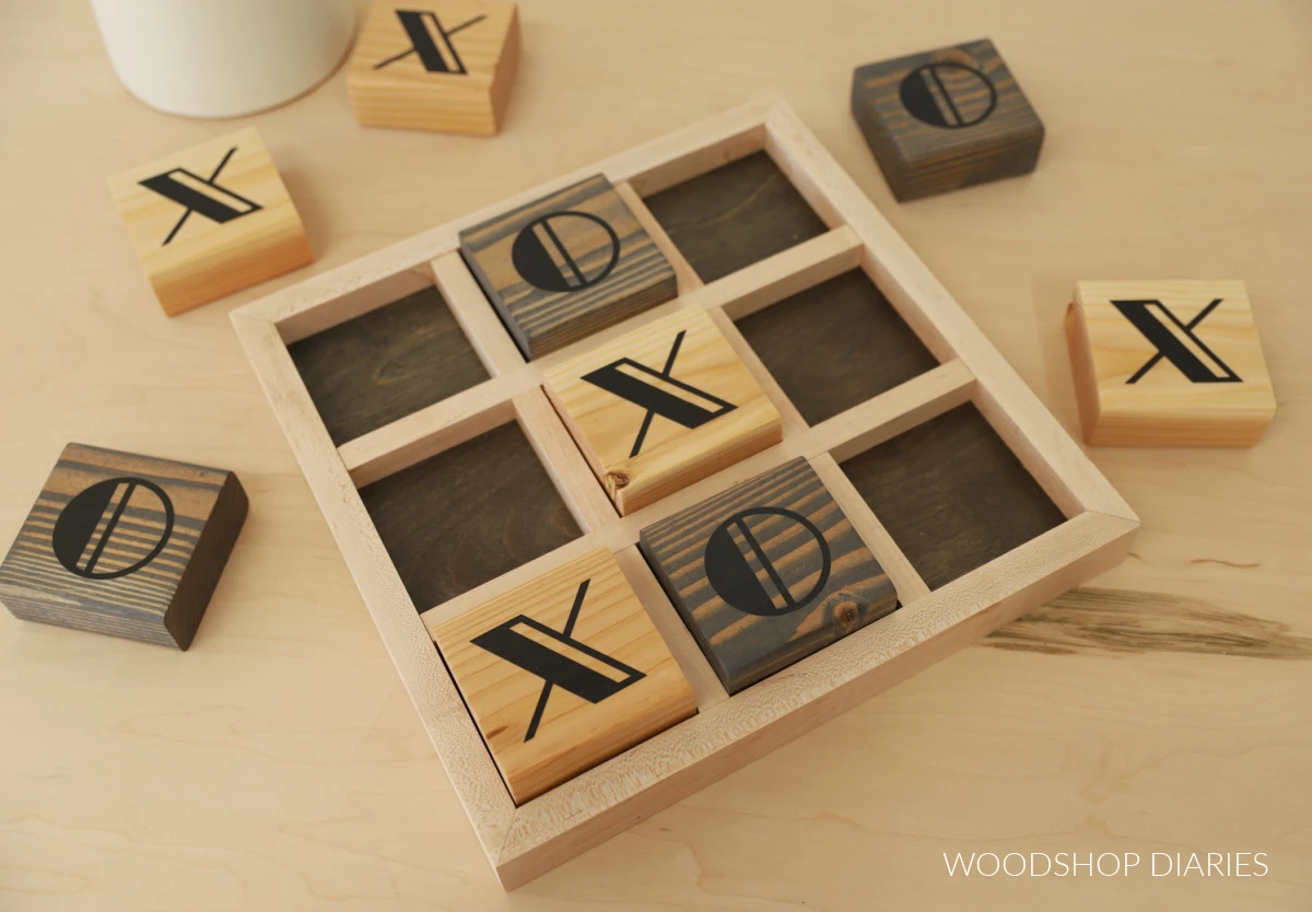 A cute, handmade wooden tabletop tic-tac-toe game sitting on a coffee table, serving as both room decor and a fun wood project for a teen's room.