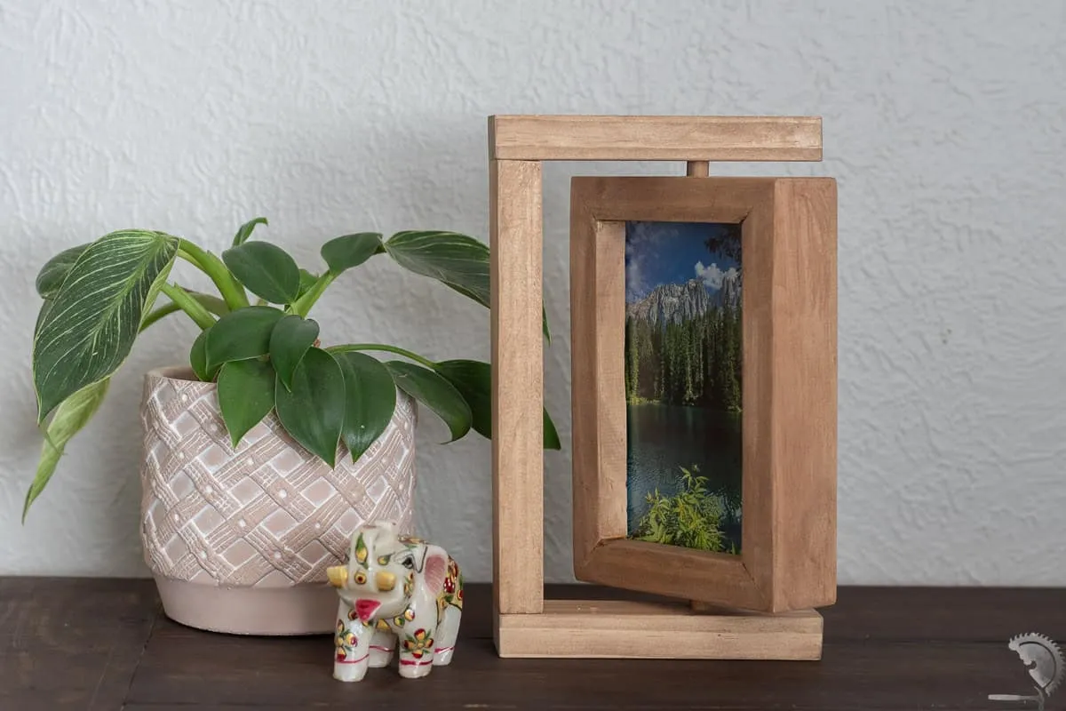 A handmade rotating wooden picture frame displaying a photo of a couple on a desk, making for a personalized and cute wood project to gift to a partner.