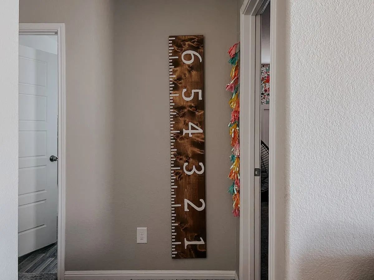 A giant wooden ruler leaning against a nursery wall to track kids' heights, making for a nostalgic and cute wood project.