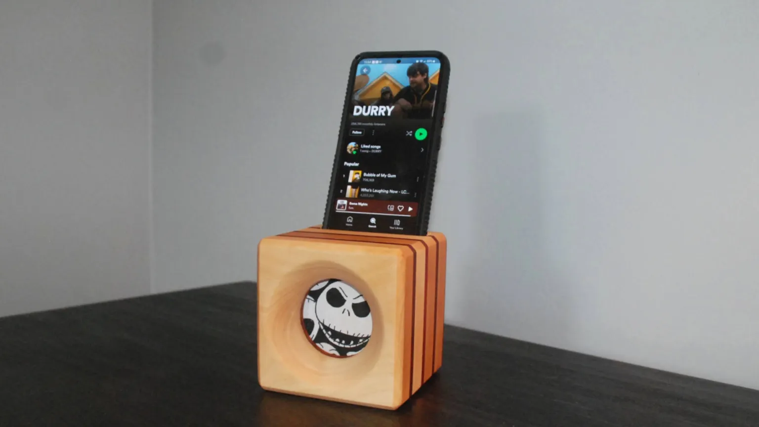 A minimalist wooden phone amplifier holding a smartphone on a counter, serving as a clever and cute wood project for gifting.