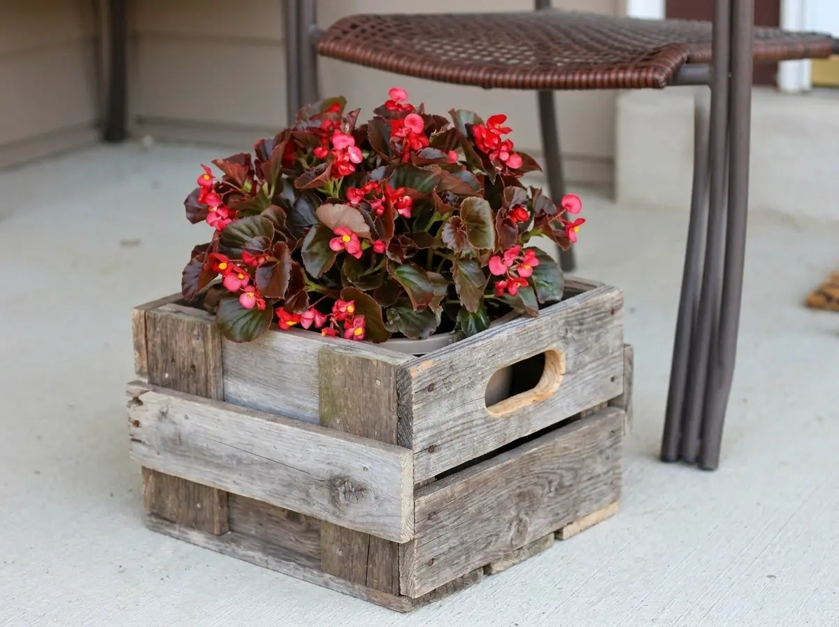 Rustic DIY pallet wood crate planter with handle cutouts holding red begonias on a porch